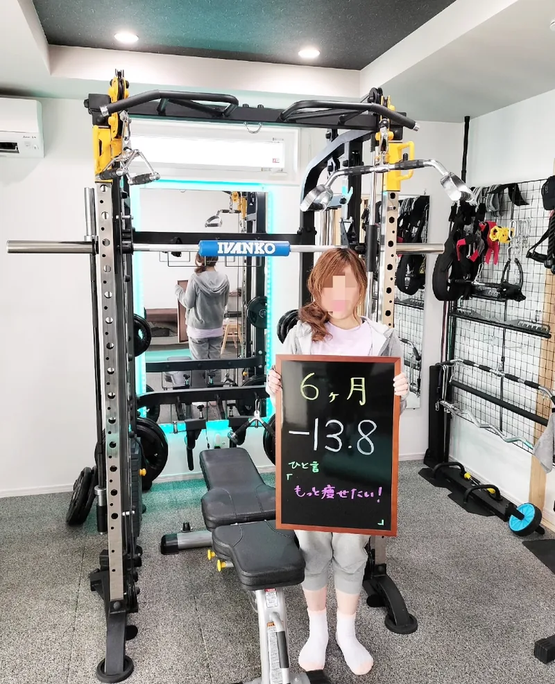 ジムで「6ヶ月 −13.8kg」と書かれた黒板を持つお客様