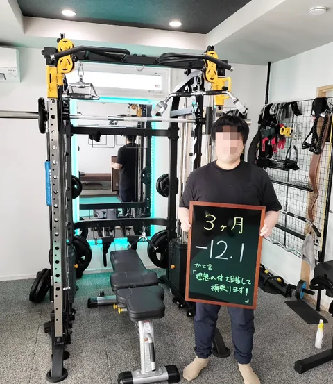 ジムで「3ヶ月 −12.1kg」と書かれた黒板を持つお客様